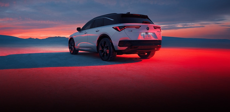 2024 Acura ZDX type S in Snowfall Pearl back parked on sand at sunset (Premium All-Electric SUV). 2024 Acura ZDX type S in Snowfall Pearl back parked on sand at sunset (Premium All-Electric SUV).